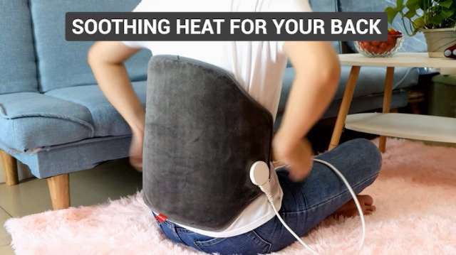person relaxing with heating pad on lower back for pain relief at home