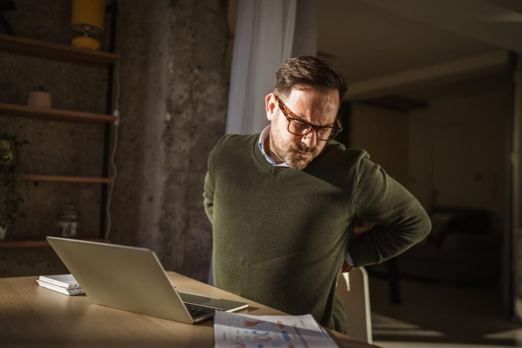 person experiencing lower back pain after sitting at desk for long hours