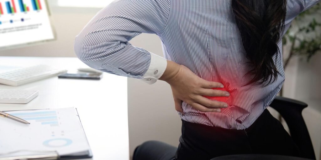 person experiencing lower back pain after sitting at desk for long time