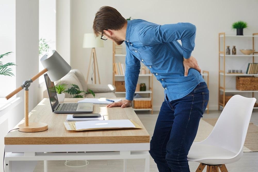 person holding lower back after sitting at desk